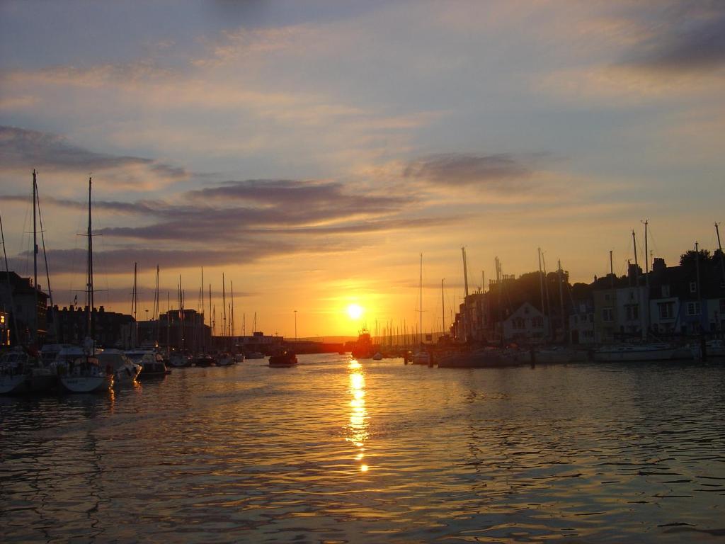 a sunset over a harbor with boats in the water at The Crown Hotel in Weymouth