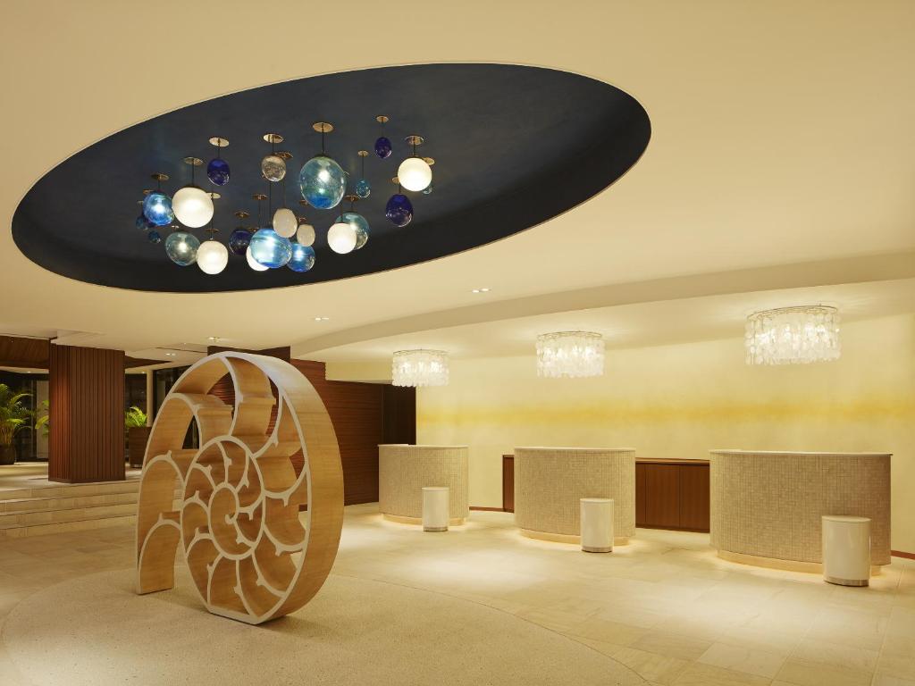 a lobby with a chandelier and a room with counters at Sheraton Okinawa Sunmarina Resort in Onna