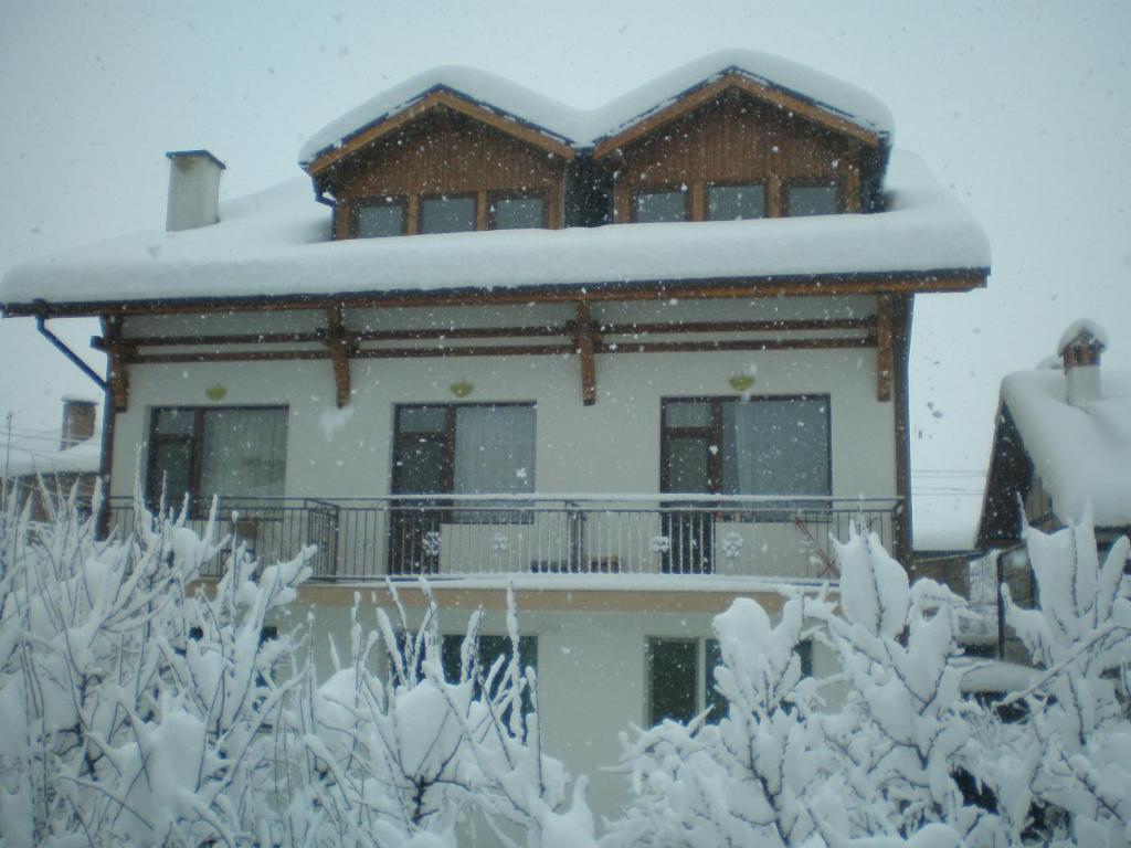 a house covered in snow in front of it at Guest House Garbevi in Dobrinishte