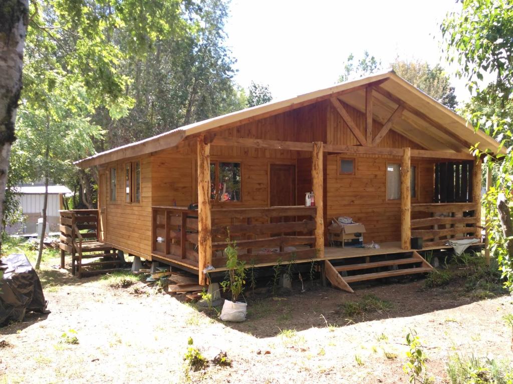 a large wooden cabin with a porch in the woods at Cabañas Coñaripe in Coñaripe