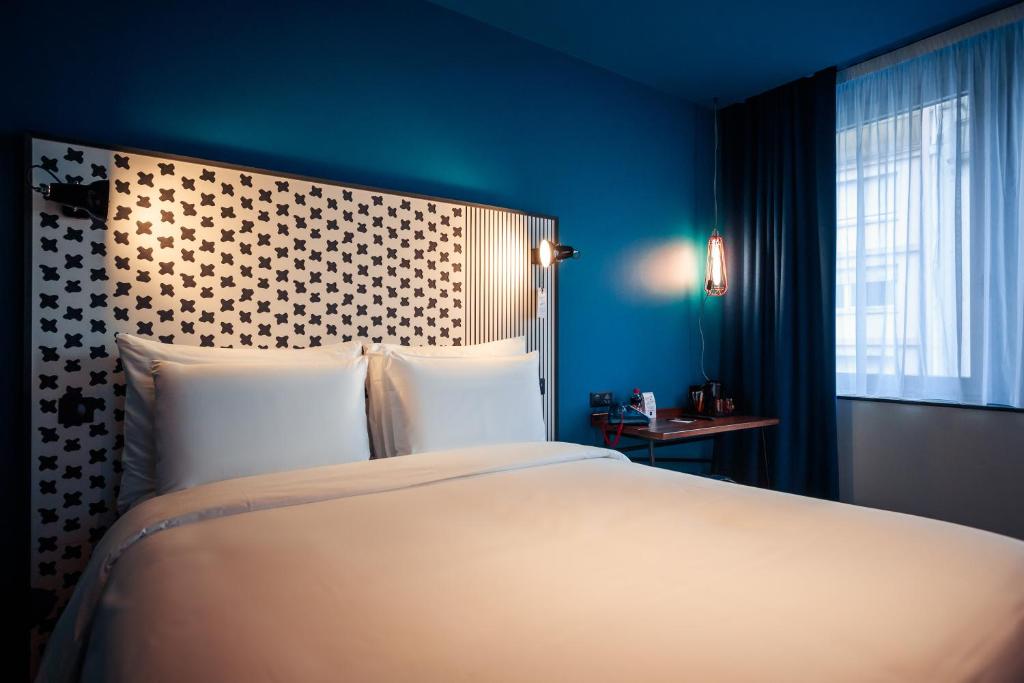 a bedroom with a large bed and a blue wall at BOMA easy living hotel By Stay Collection in Strasbourg