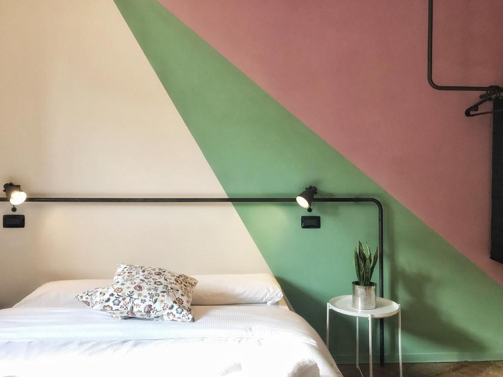 a bedroom with a green and pink wall with a bed at Hotel Cappello in Cesena