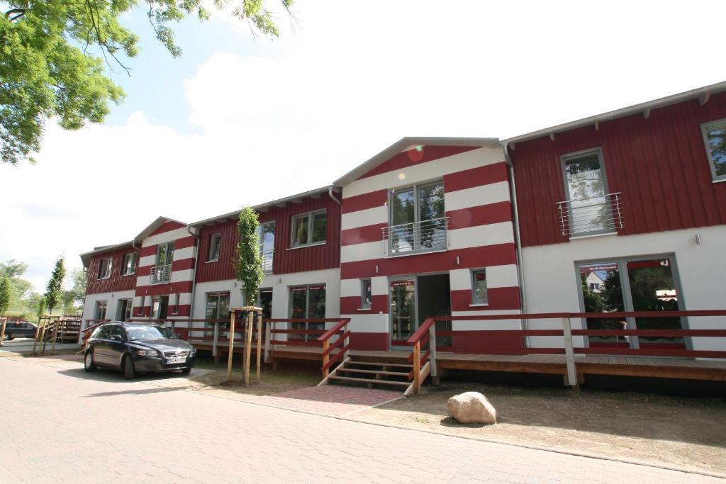 a red and white building with a car parked in front at Appartement Werft & Mee(h)r Bootsbau Rügen in Lauterbach