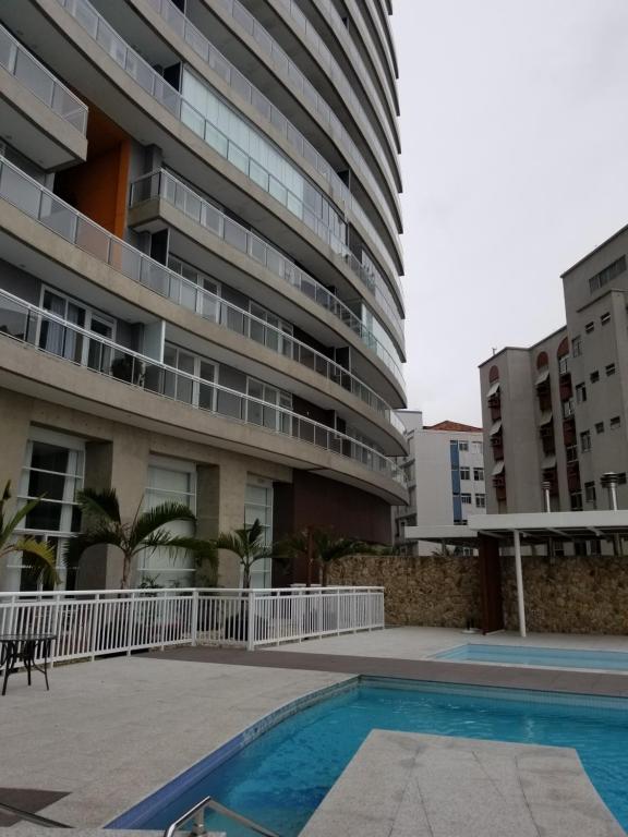 a building with a swimming pool in front of a building at Unlimited Ocean Front in Santos