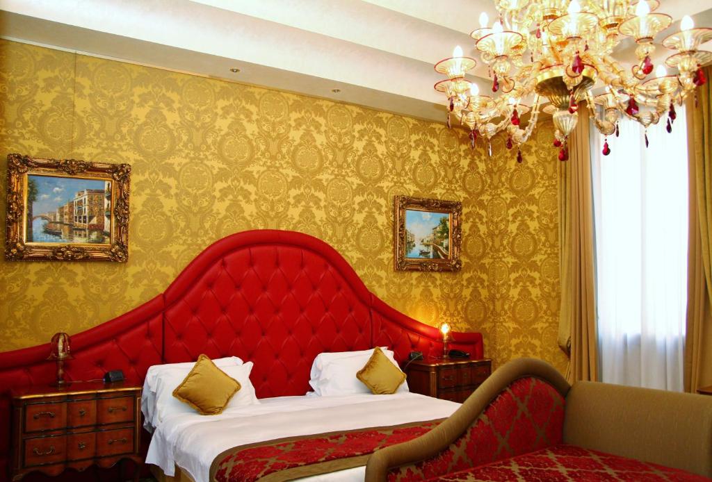 a bedroom with a red bed and a chandelier at Pesaro Palace in Venice