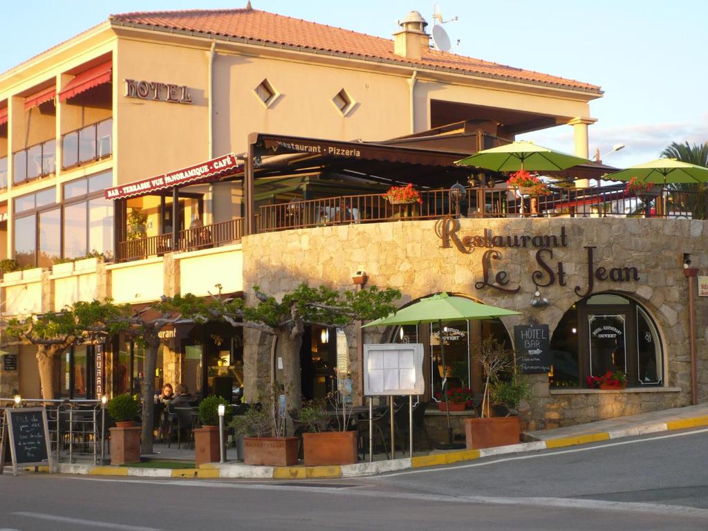 a building with green umbrellas on the side of a street at Hotel & Restaurant le Saint Jean in Cargèse