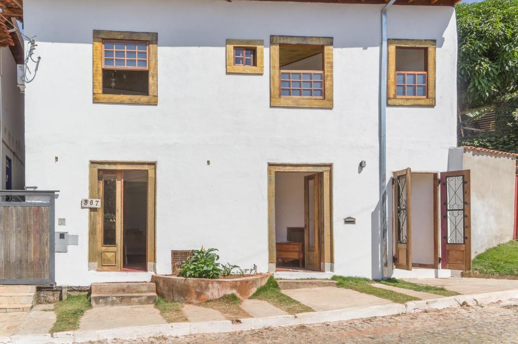 ein weißes Haus mit Holztüren und Fenstern in der Unterkunft Pouso copo de leite in Tiradentes