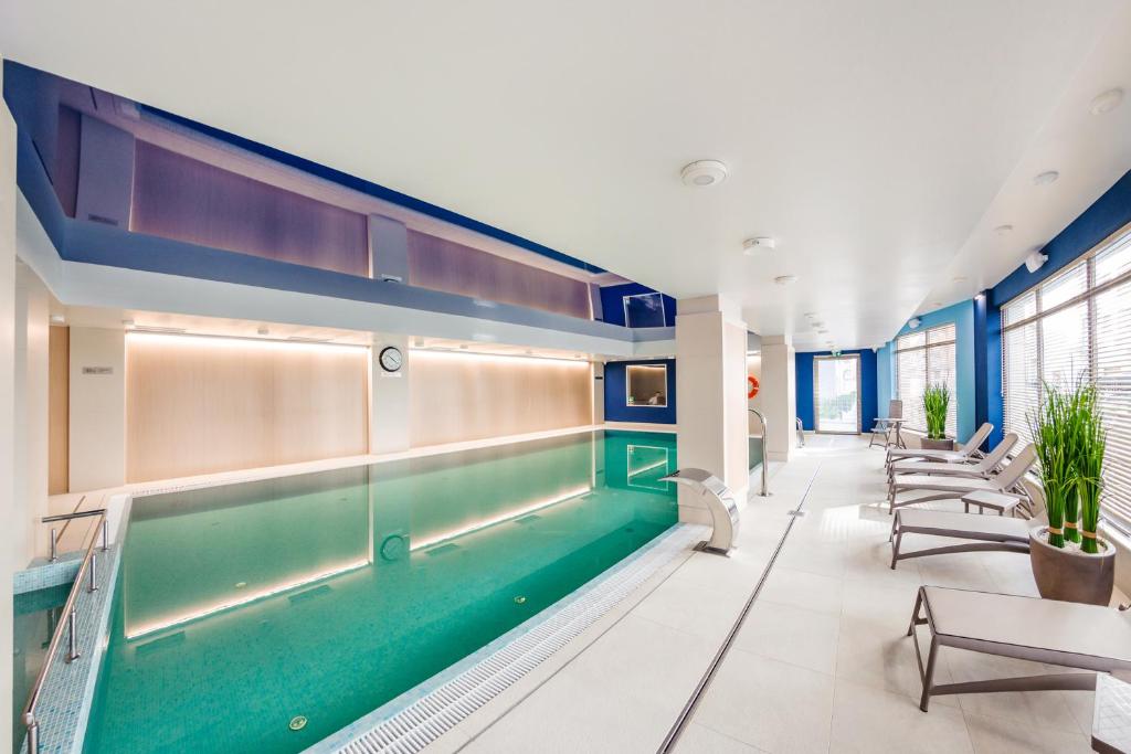 an indoor pool in a building with chairs and tables at Apartamenty Sun & Snow Nowa Motława in Gdańsk