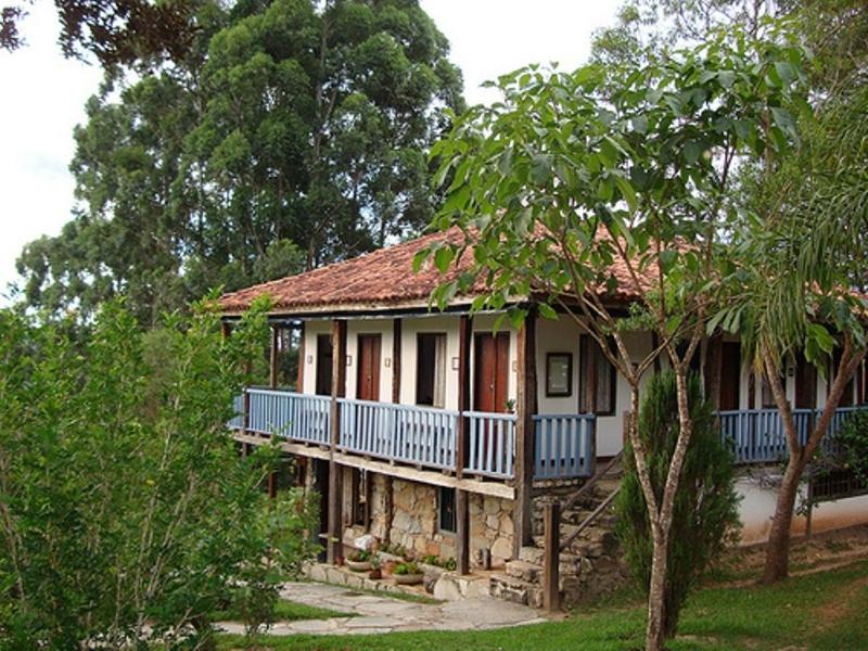 ein kleines Haus mit einer Veranda und einem Balkon in der Unterkunft Pousada do Capão in São Gonçalo do Rio das Pedras