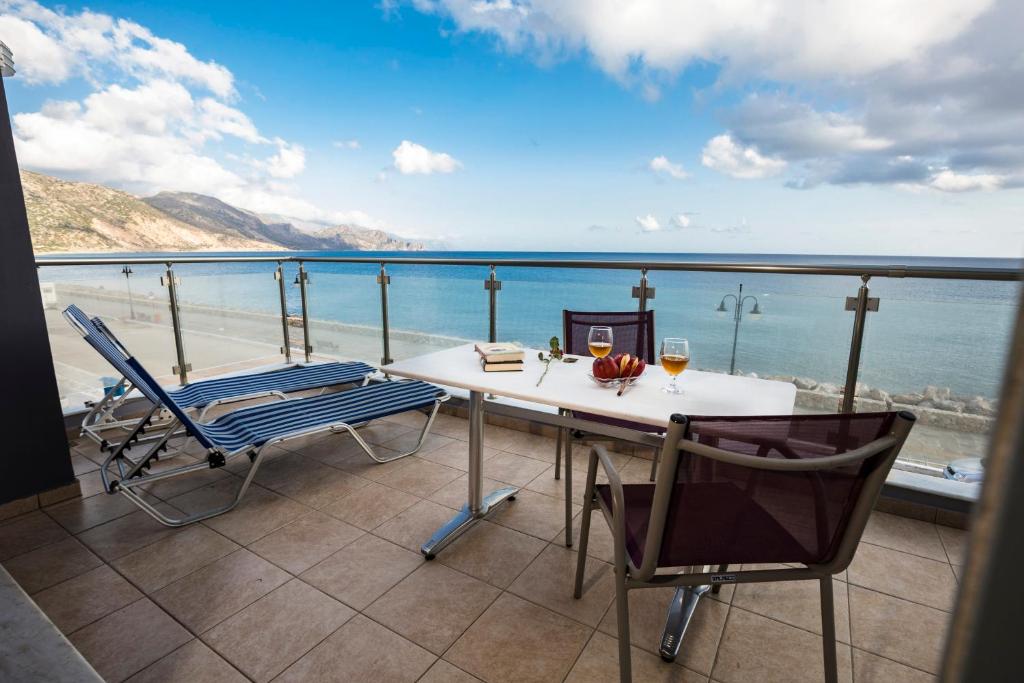 a table and chairs on a balcony with a view of the ocean at Paleochora Apartments in Palaiochóra