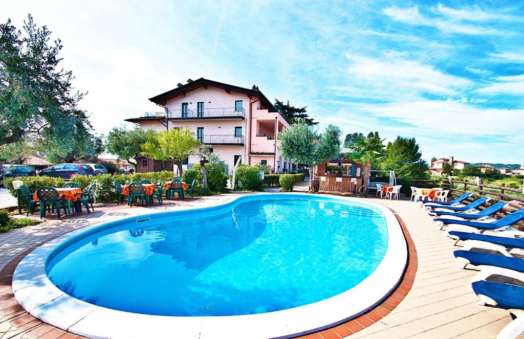 a swimming pool with chairs and a building in the background at Residence Bellavista in Manerba del Garda