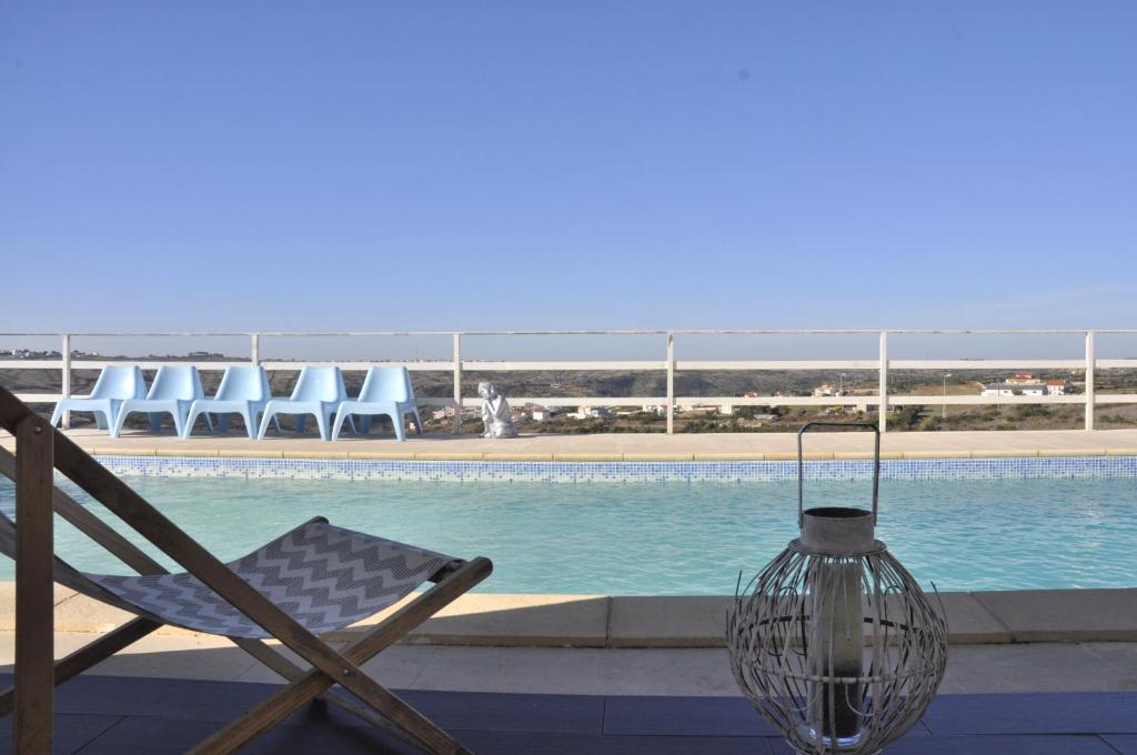 uma cadeira e um vaso junto a uma piscina em Casa Serra e Mar em Mafra