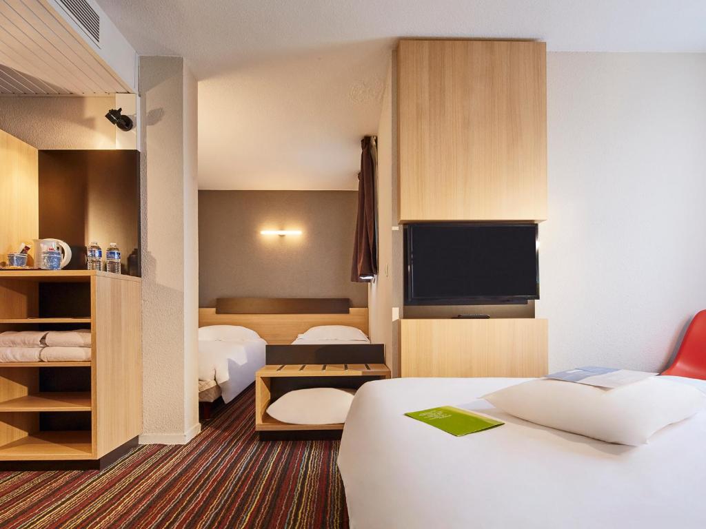 a hotel room with two beds and a flat screen tv at Kyriad Tours Sud - Chambray Lès Tours in Chambray-lès-Tours