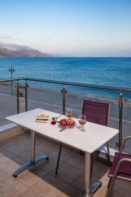 a table with two glasses of wine on a balcony with the ocean at Paleochora Apartments in Palaiochora