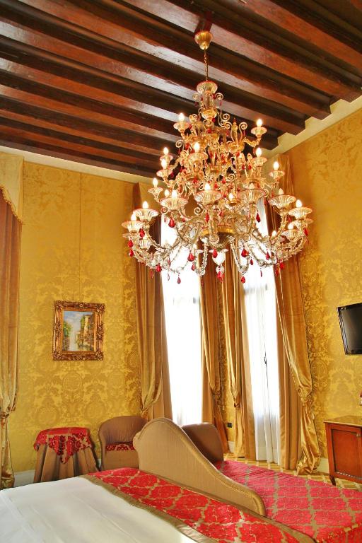 a bedroom with a chandelier and yellow walls at Pesaro Palace in Venice