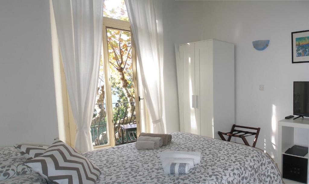 a white bedroom with a bed and a window at Hotel Firenze Lugano in Lugano