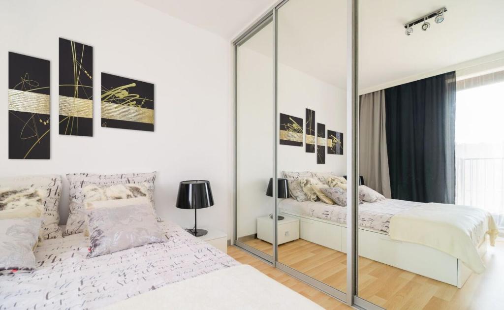 a white bedroom with a mirror and two beds at ArtApart Centrum Wrocław in Wrocław