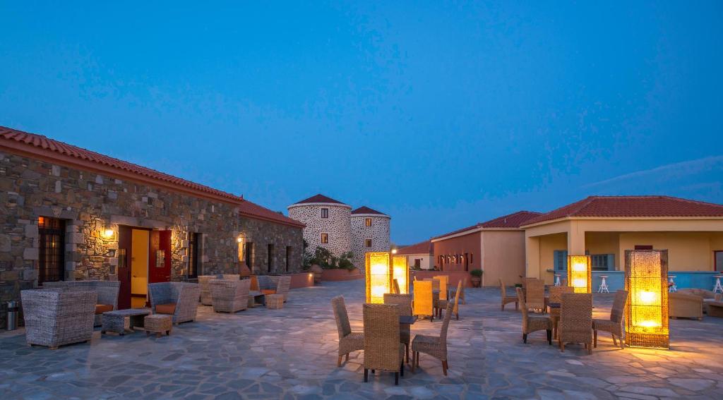 a patio with chairs and tables and lights at night at Varos Village Boutique Hotel in Város