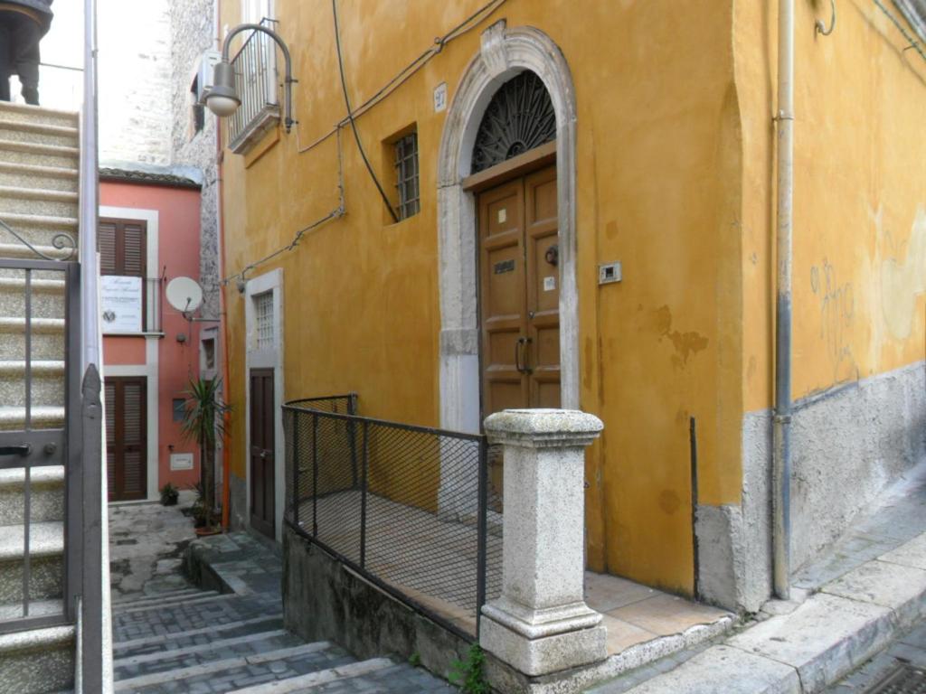 a yellow building with a wooden door on a street at resort san paolo in Modica