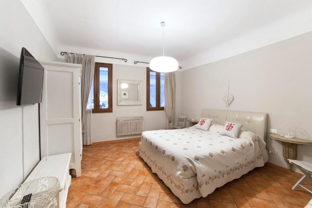 a white bedroom with a bed and a television at Exclusive Apartment San Lorenzo in Florence