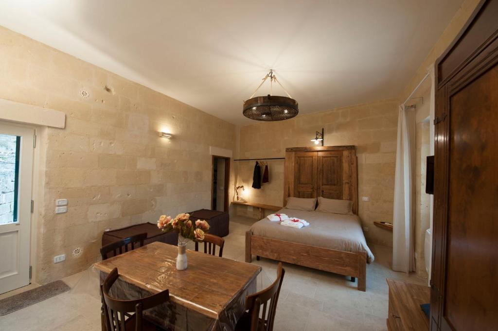 a room with a bed and a table and a bed at Sassi e Virtù in Matera
