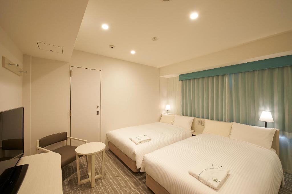 Habitación de hotel con 2 camas y escritorio en Sotetsu Fresa Inn Ginza Sanchome, en Tokio