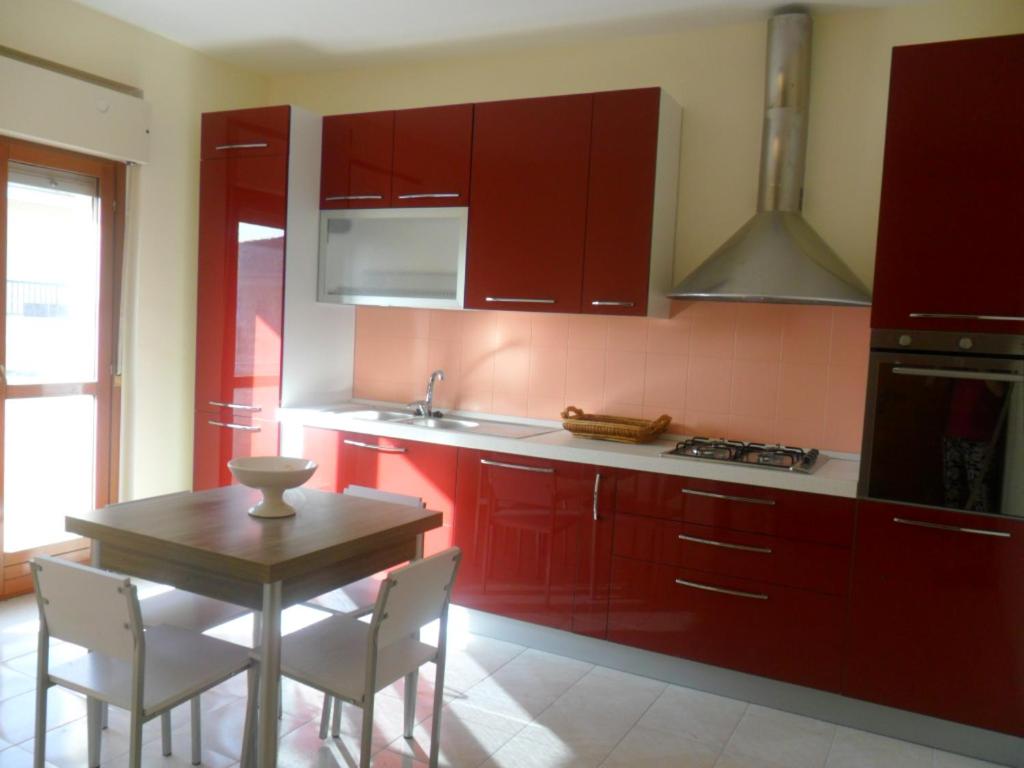 una cocina con armarios rojos y una mesa con sillas. en Appartamento Sacro Cuore, en Módica