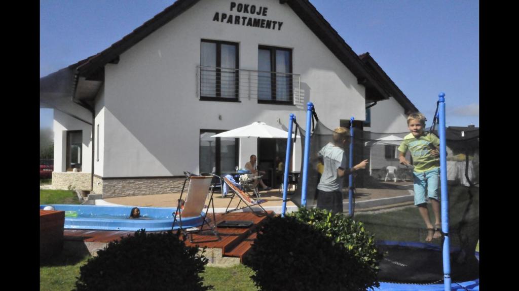 dos chicos jugando en un patio de juegos en frente de una casa en Apartamenty i Pokoje Na Letniej, en Darłowo