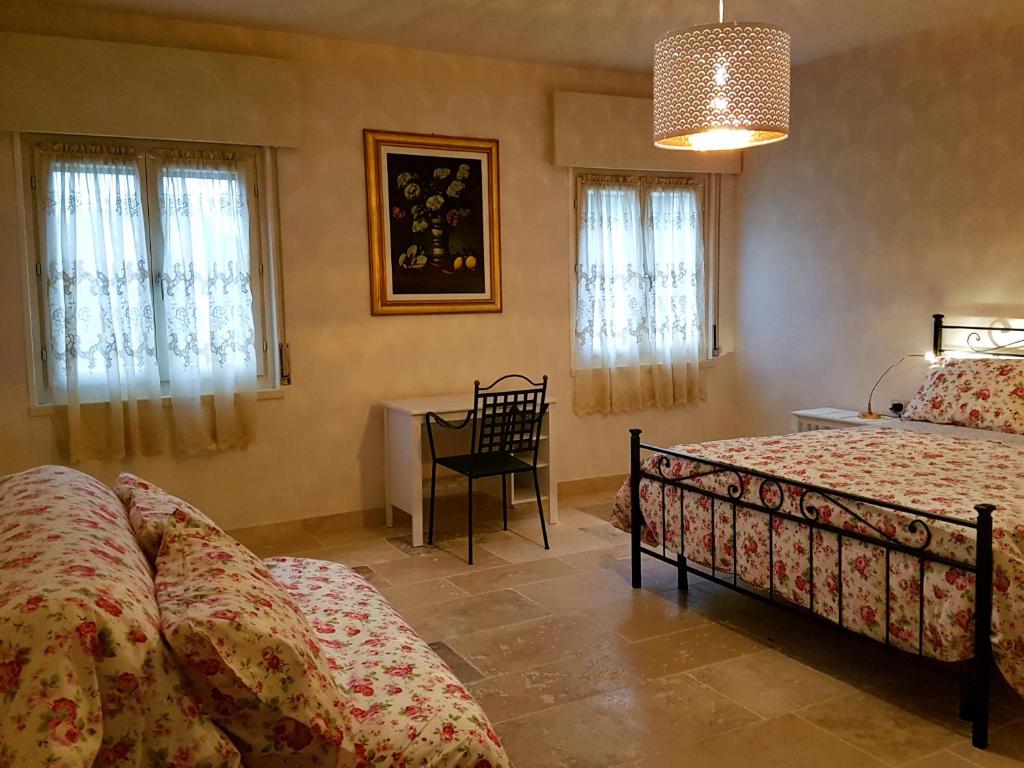 a bedroom with two beds and a table and windows at Foresteria Borgo Delle Grazie in Curtatone