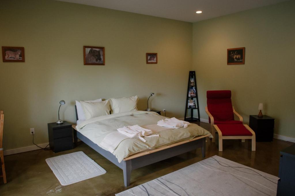 a bedroom with a bed and a red chair at Baergnaescht B&B in Osoyoos