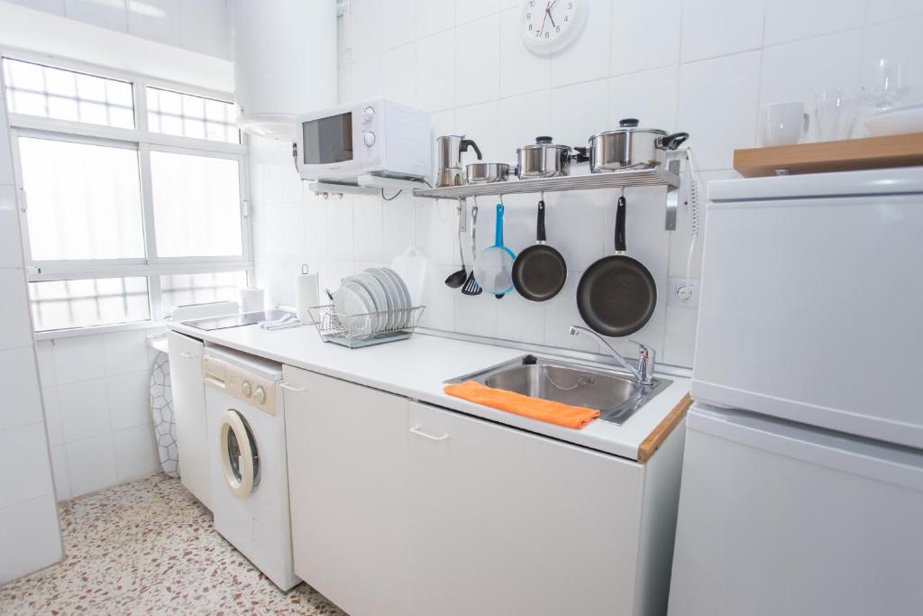 a white kitchen with a sink and a dishwasher at Multi Apartamentos La Kasbah in Jerez de la Frontera