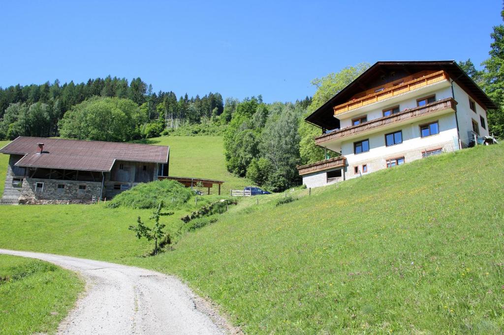 ein Haus auf einem Hügel neben einer unbefestigten Straße in der Unterkunft Laxhube in Gmünd in Kärnten