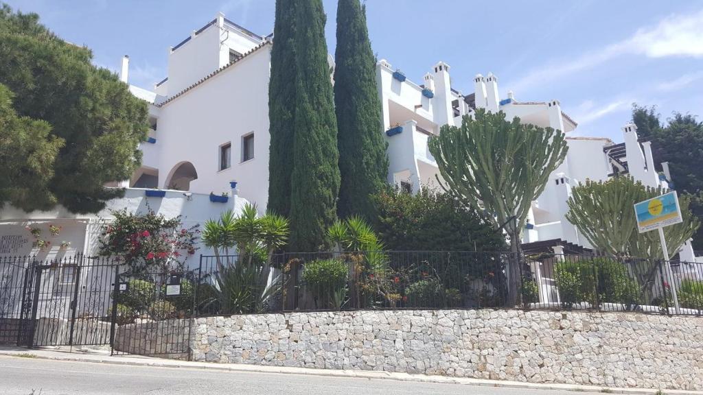 ein weißes Gebäude mit Bäumen und einer Steinmauer in der Unterkunft Pueblo Evita Hill in Benalmádena