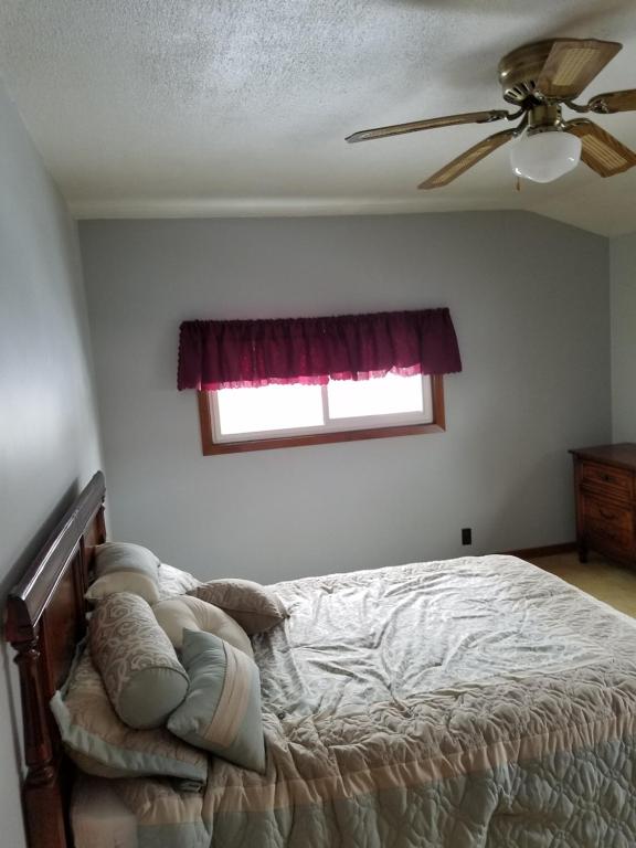 Schlafzimmer mit einem Bett, einem Deckenventilator und einem Fenster in der Unterkunft Cozy cottage on Lake Winnebago in Fond du Lac