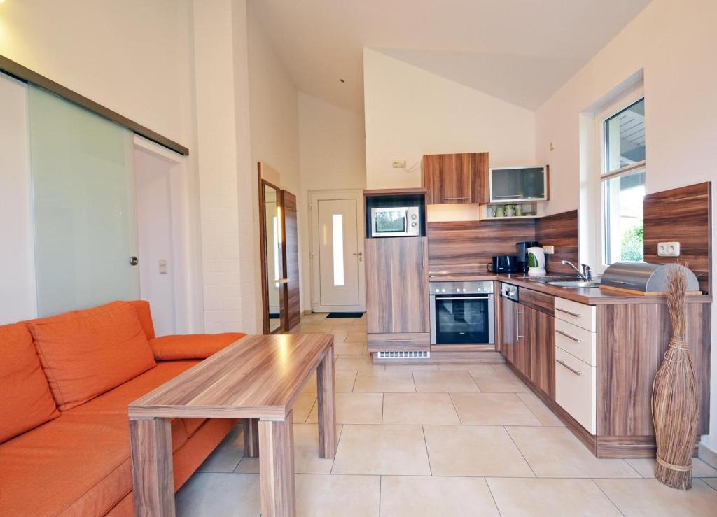 ツィノヴィッツにあるHaus Ostseekristall Wohnung Smaragdのリビングルーム(オレンジ色のソファ付)、キッチンが備わります。