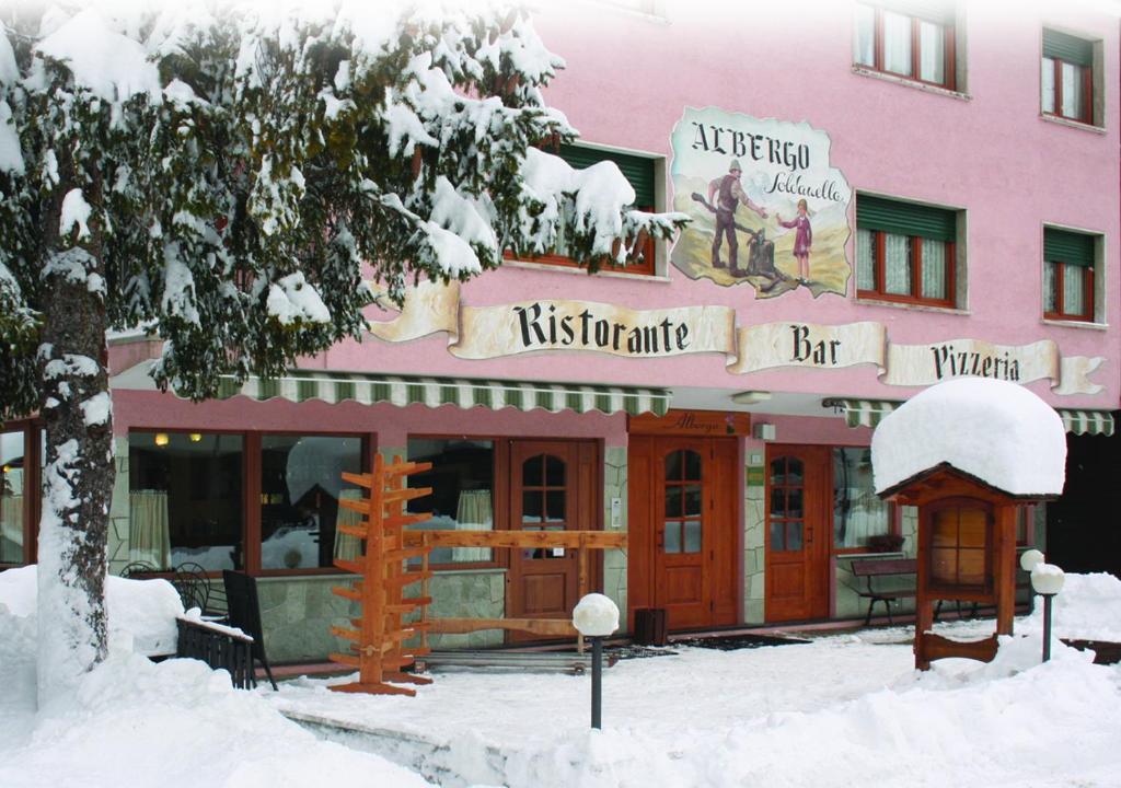 un ristorante coperto di neve di fronte a un edificio di Albergo Soldanella a Madesimo