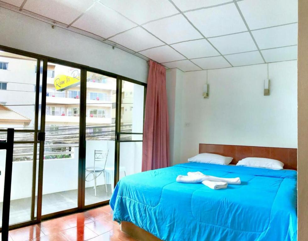 a bedroom with a blue bed and a balcony at Malee House and Restaurant in Pattaya