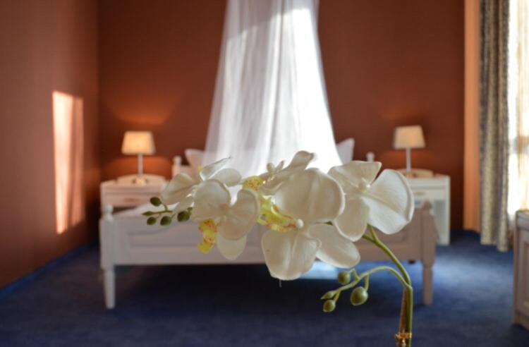 Una habitación con una cama con flores blancas. en Hotel Shterev Sopot, en Sopot