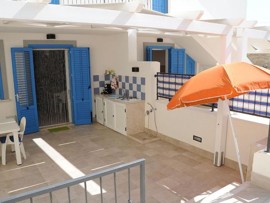 a balcony with an orange umbrella and blue doors at Casa vacanza Irma Dario in San Vito lo Capo