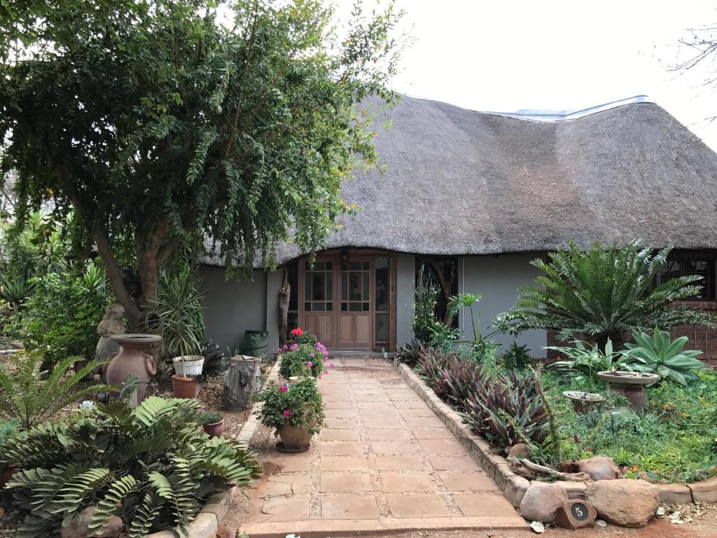 a house with a thatched roof with plants and flowers at Weltevreden Country Guest Lodge in Groblersbrug