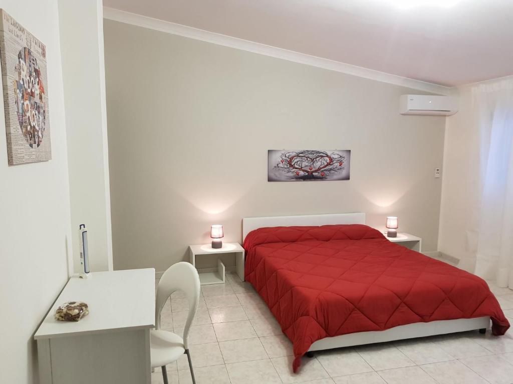 1 dormitorio con 1 cama roja con 2 mesas y sillas en XXI Agosto Home, en Reggio Calabria