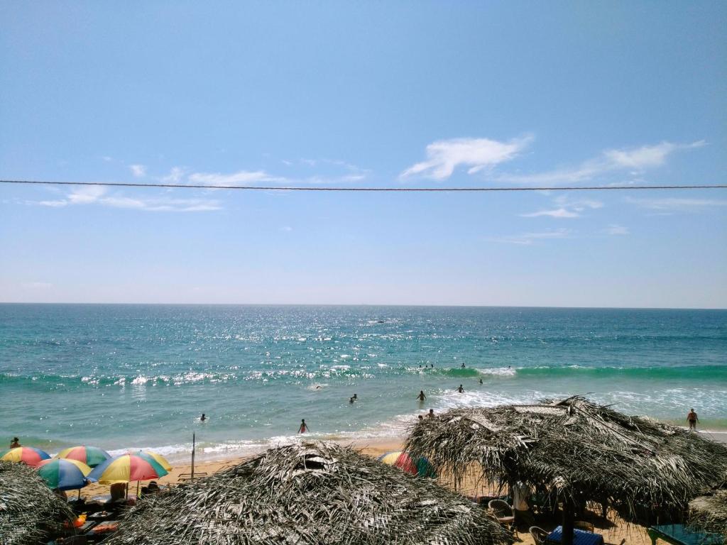 a beach with umbrellas and people in the ocean at Sunnys Beach Guest House in Hikkaduwa