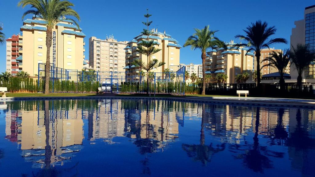 a large swimming pool with palm trees and buildings at Los Miradores in La Manga del Mar Menor