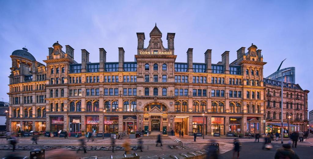 un gran edificio con gente caminando delante de él en Roomzzz Manchester Victoria en Mánchester