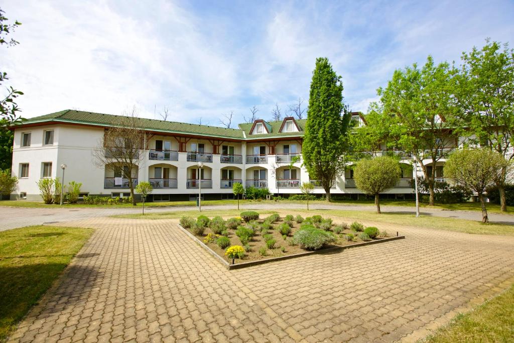un gran edificio blanco con un jardín delante de él en Auguszta Hotel és Diákszálló, en Debrecen