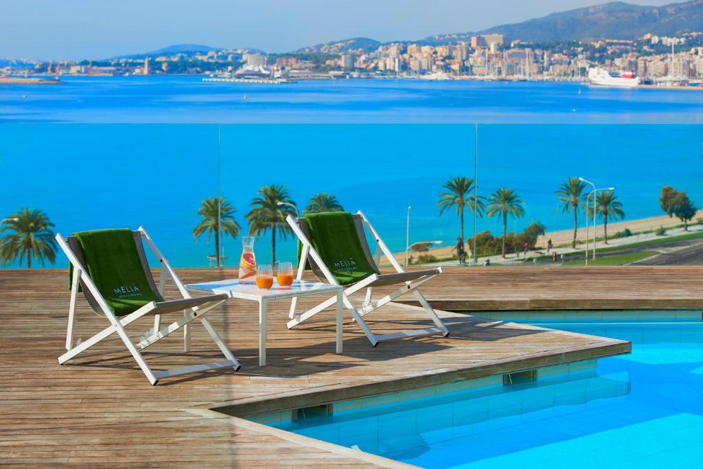 Duas cadeiras e uma mesa num deque ao lado de uma piscina em Melia Palma Bay em Palma de Maiorca