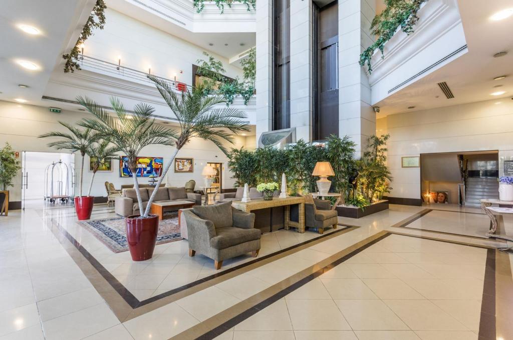 a lobby with chairs and plants in a building at Riviera Hotel in Carcavelos