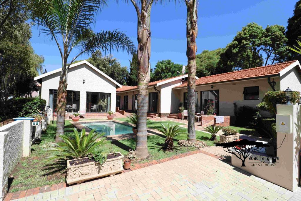 a house with a swimming pool and palm trees at Acacia Grove Guest House in Johannesburg