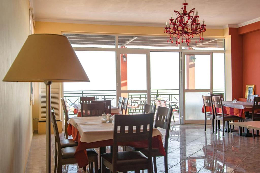 a dining room with tables and chairs and a chandelier at Saint Catherine Hotel in Pythagoreio