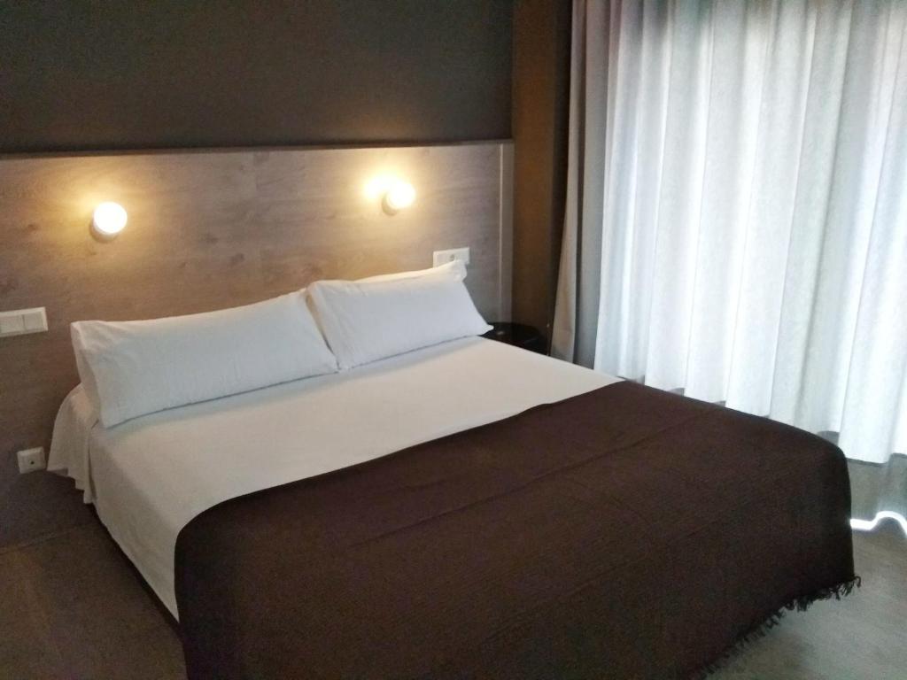 una camera da letto con un letto grande con cuscini bianchi di Hotel Delicias a Saragozza